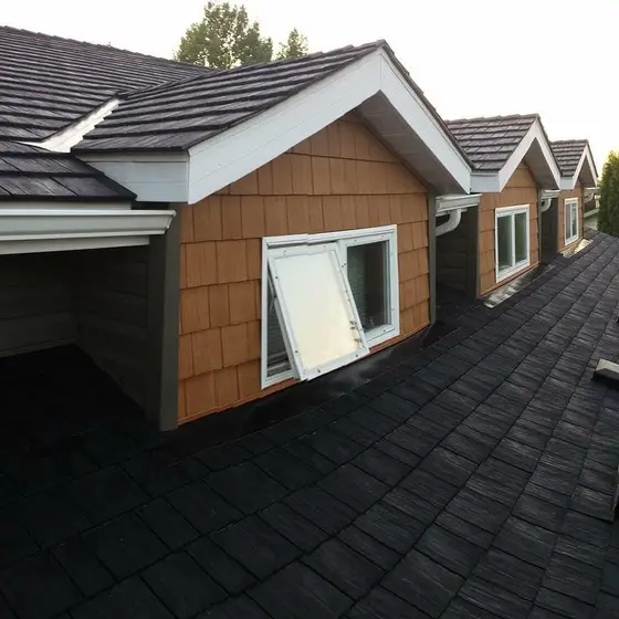 Tan cedar-shake gable dormers with white trim above a new dark asphalt roof